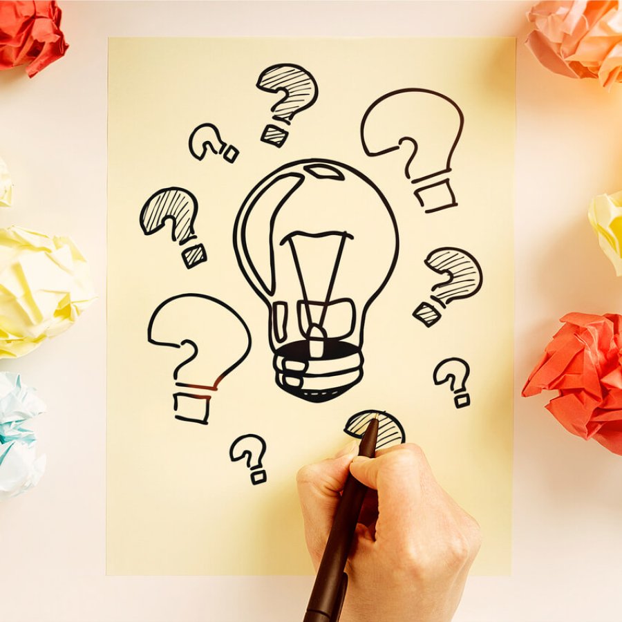 Idea concept Idea concept with hand drawing lightbulb and question marks sketch on paper sheet surrounded with colorful crumpled paper balls