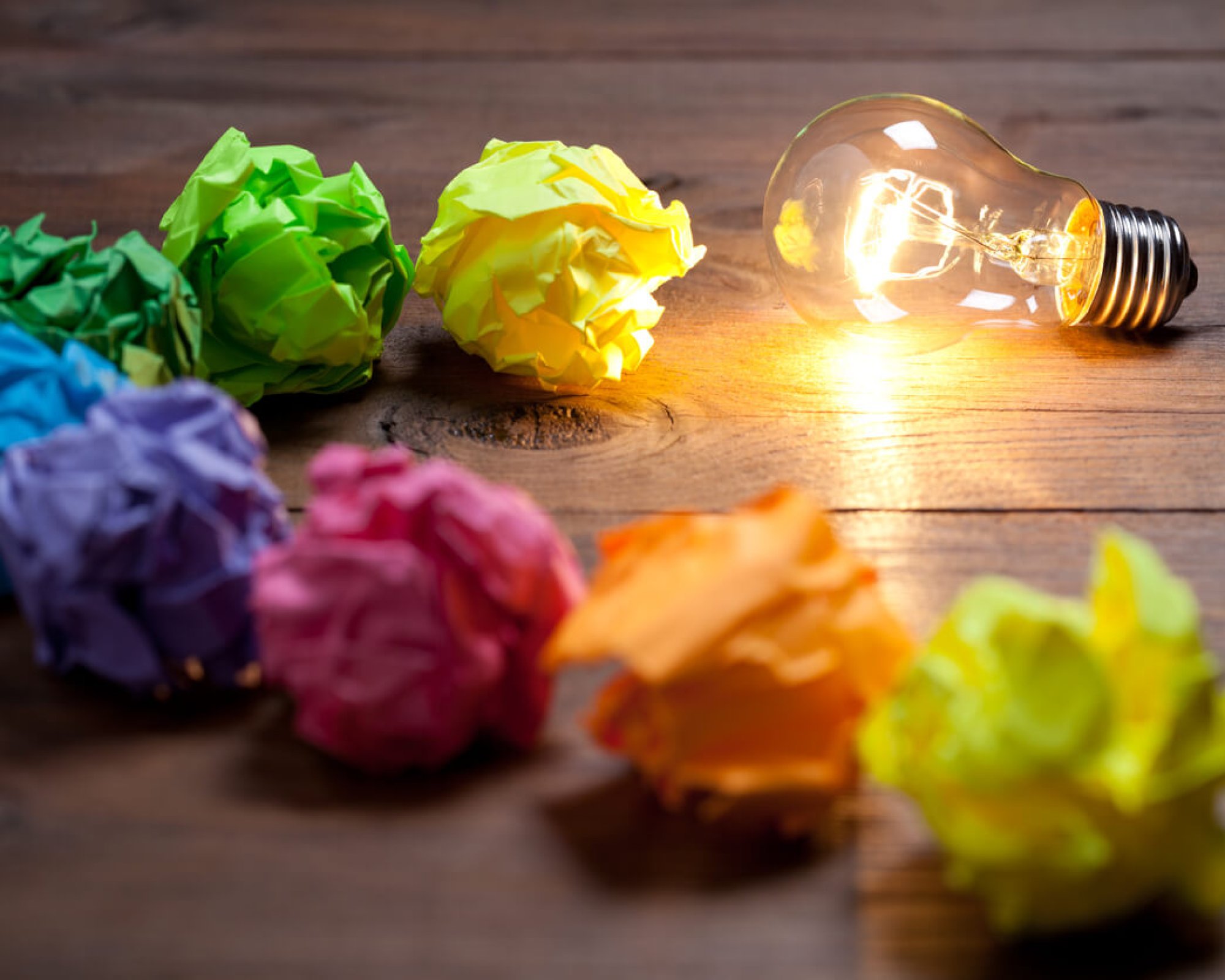 Incandescent bulb and colorful notes on old wooden table. This file is cleaned and retouched.