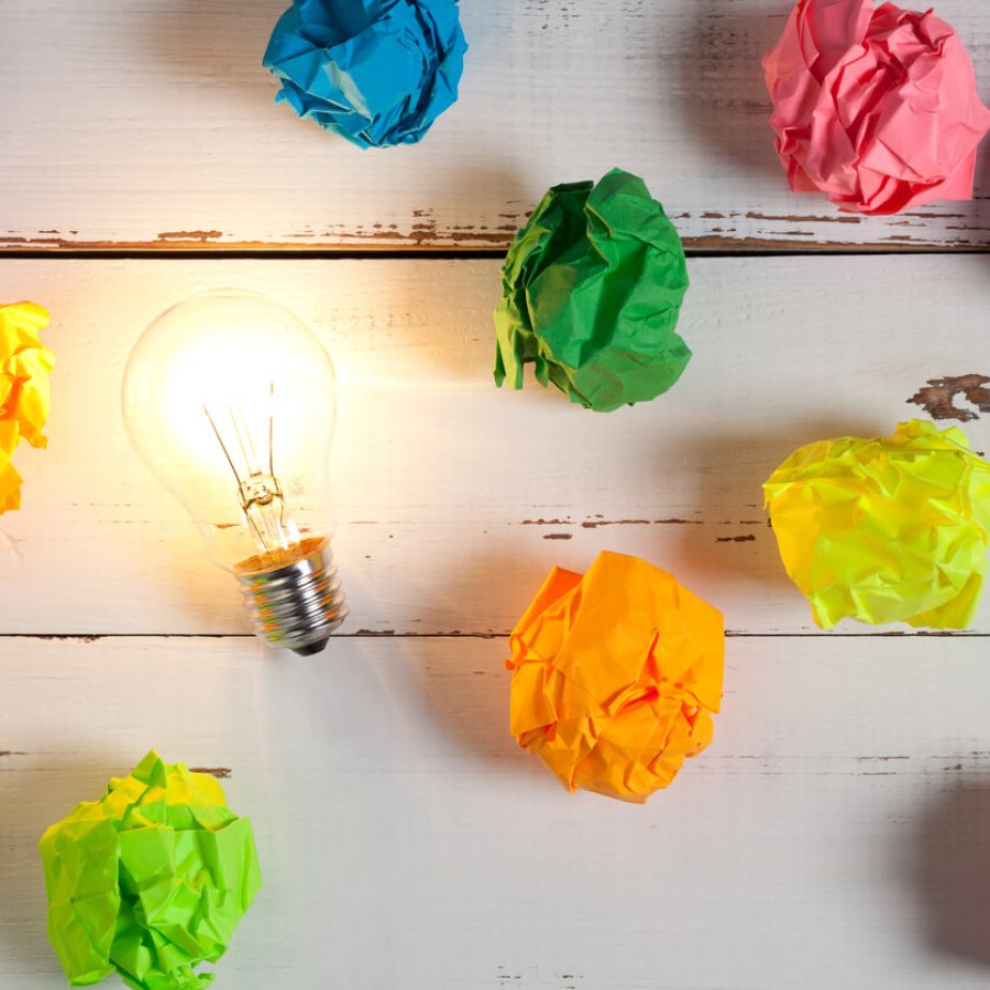 Incandescent bulb and colorful notes on white wooden table Incandescent bulb and colorful notes on white wooden table. This file is cleaned and retouched.